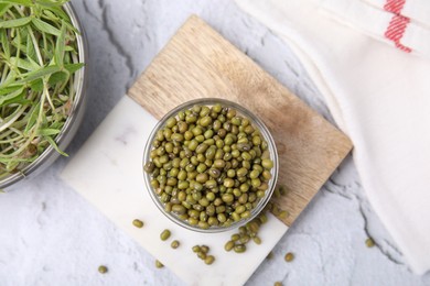 Photo of Glass bowl with mung beans and coaster on white textured table, flat lay