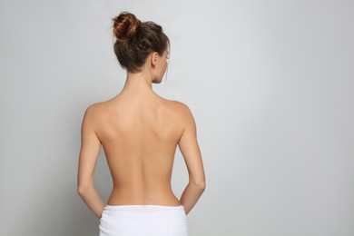 Photo of Back view of woman with perfect smooth skin on light grey background, space for text. Beauty and body care