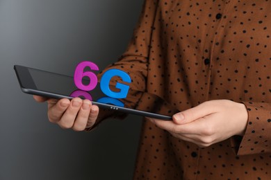 Photo of 6G technology, Internet concept. Woman holding tablet with number and letter on grey background, closeup