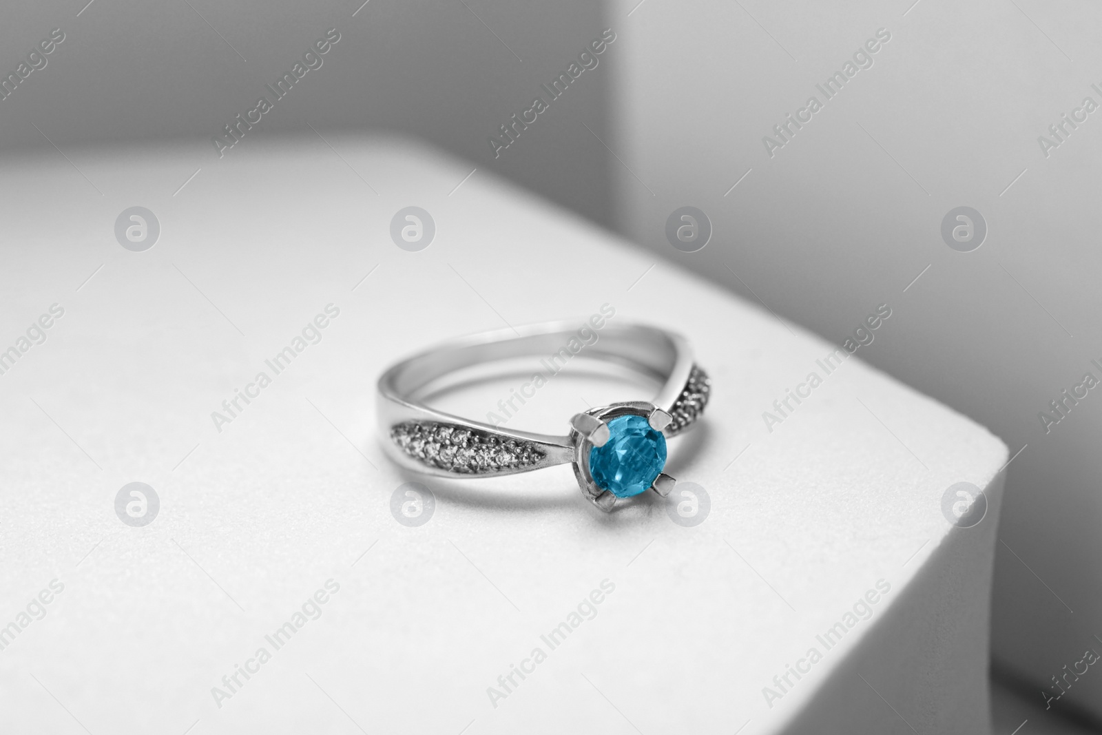 Photo of Beautiful ring with light blue gemstone on white podium. Luxury jewelry