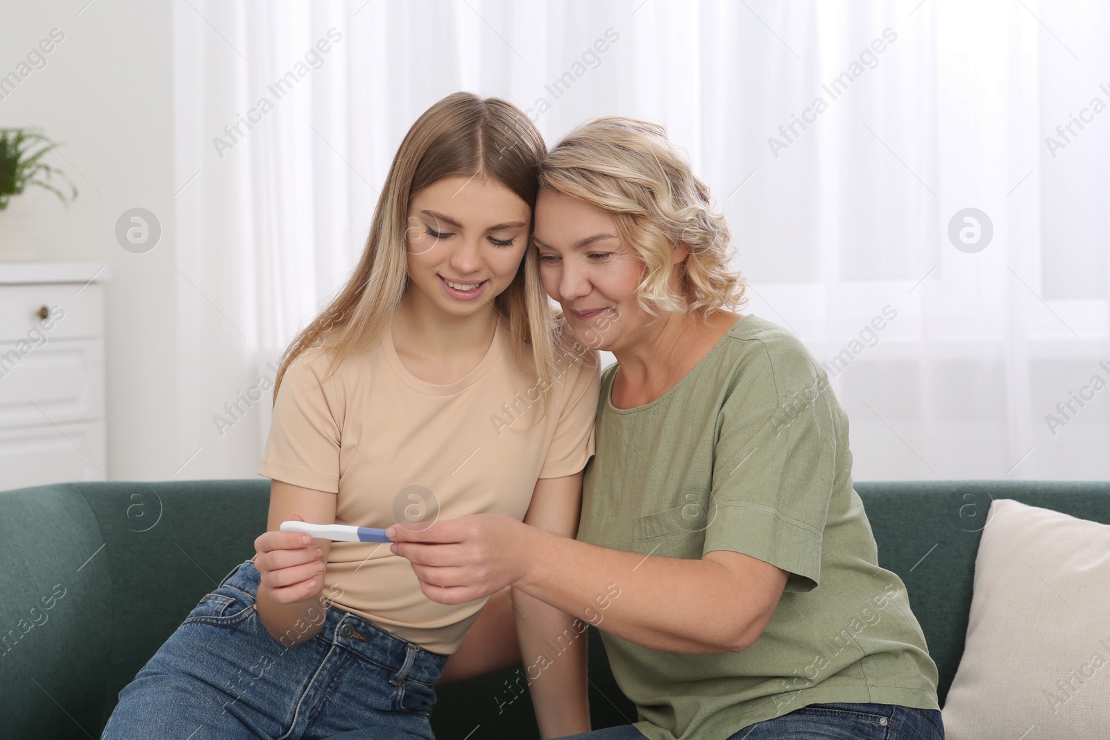 Photo of Young woman showing her mother pregnancy test at home. Grandparent reaction to future grandson