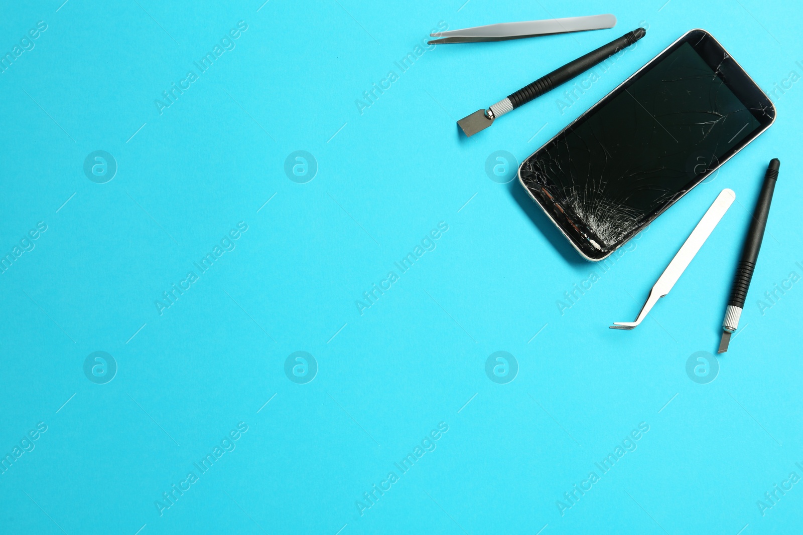 Photo of Damaged smartphone and repair tool set on light blue background, flat lay. Space for text