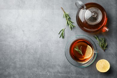 Aromatic herbal tea with rosemary and lemon on grey table, flat lay. Space for text