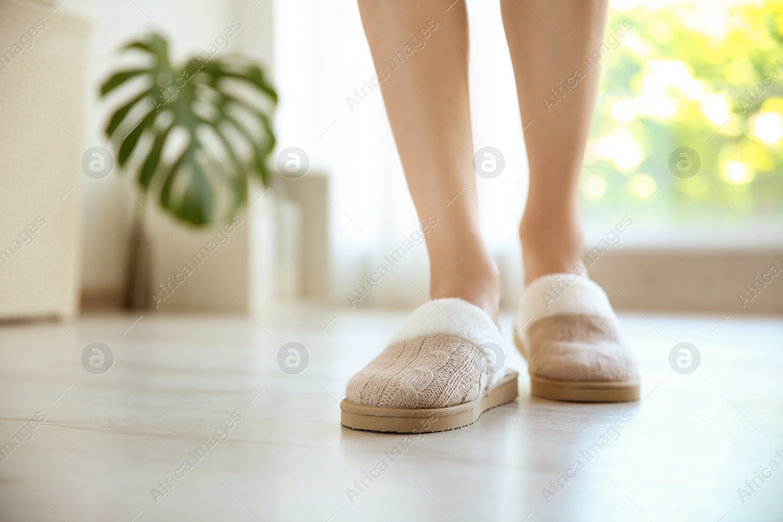 Photo of Young woman with sexy legs in soft slippers at home