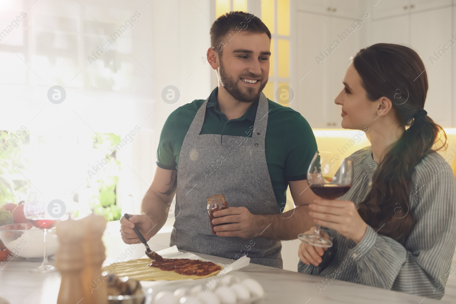 Photo of Lovely young couple cooking pizza together in kitchen