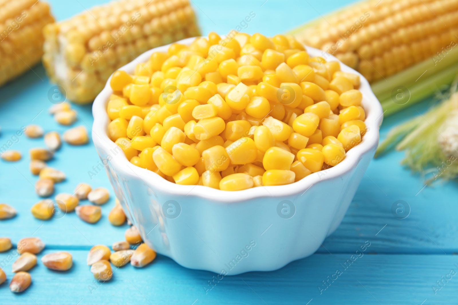 Photo of Bowl with corn kernels on blue wooden table