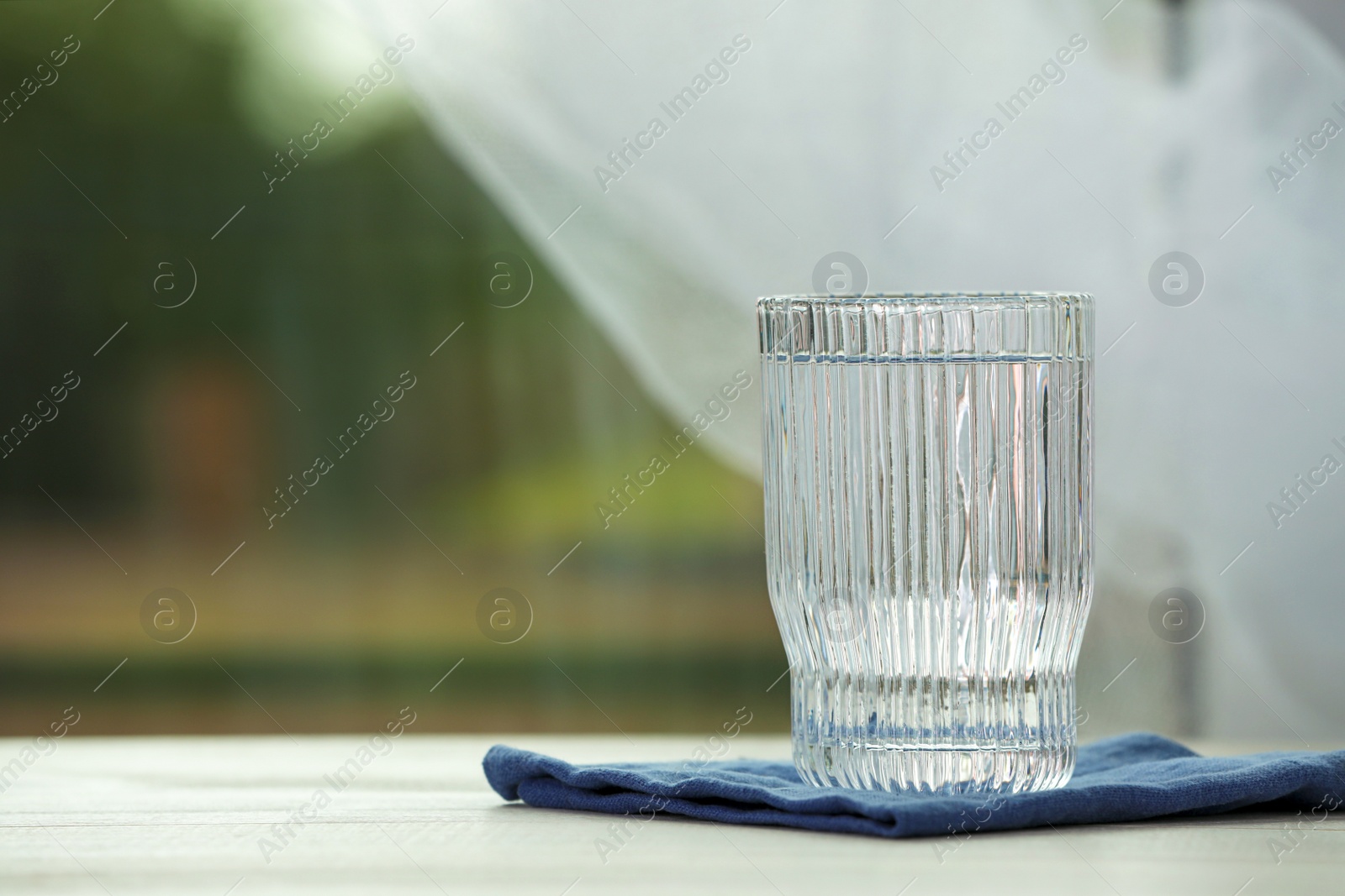 Photo of Glass of pure water on white table, space for text