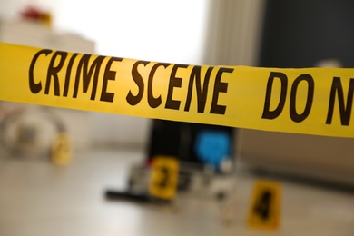 Photo of Crime scene with evidences and criminologist case, focus on yellow tape