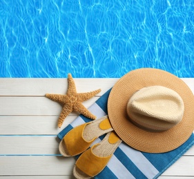 Image of Beach accessories on white wooden deck near swimming pool, flat lay 