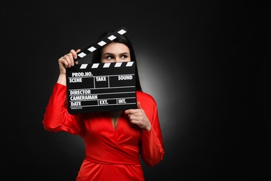 Actress with clapperboard on black background, space for text. Film industry