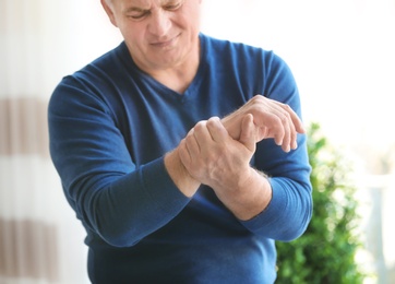 Mature man suffering from hand pain at home