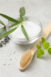 Photo of Bamboo toothbrush, sea salt and herbs on light grey table, closeup