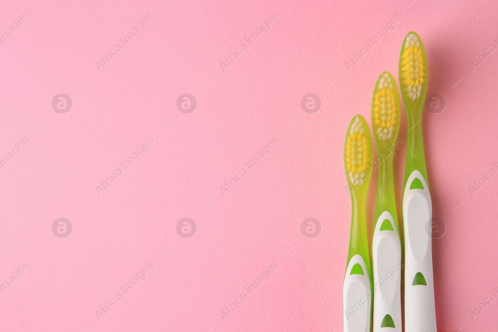 Photo of Toothbrushes on pink background, flat lay. Space for text