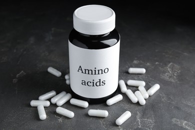 Photo of Amino acid pills and jar on grey table