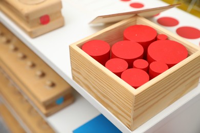 Set of wooden geometrical objects and other montessori toys on shelves, closeup