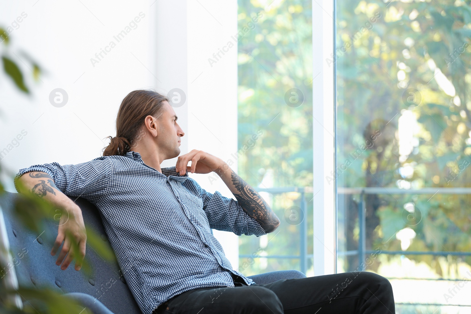 Photo of Young man with stylish tattoos at home