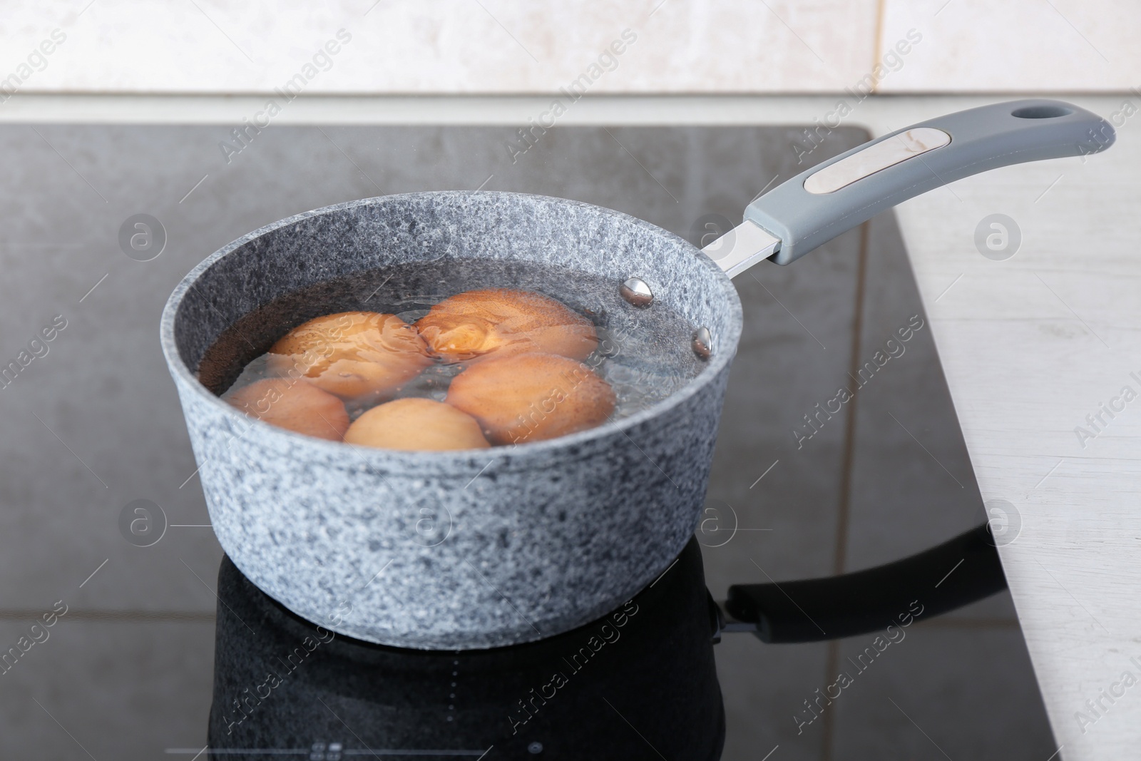 Photo of Chicken eggs boiling in saucepan on electric stove
