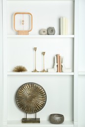 White shelves with books and different decor indoors. Interior design