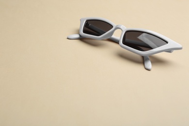 Photo of Stylish sunglasses on beige background, space for text. Fashionable accessory