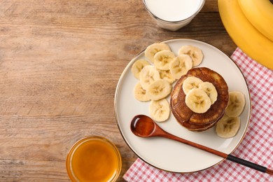 Photo of Plate of banana pancakes with honey on wooden table, flat lay. Space for text