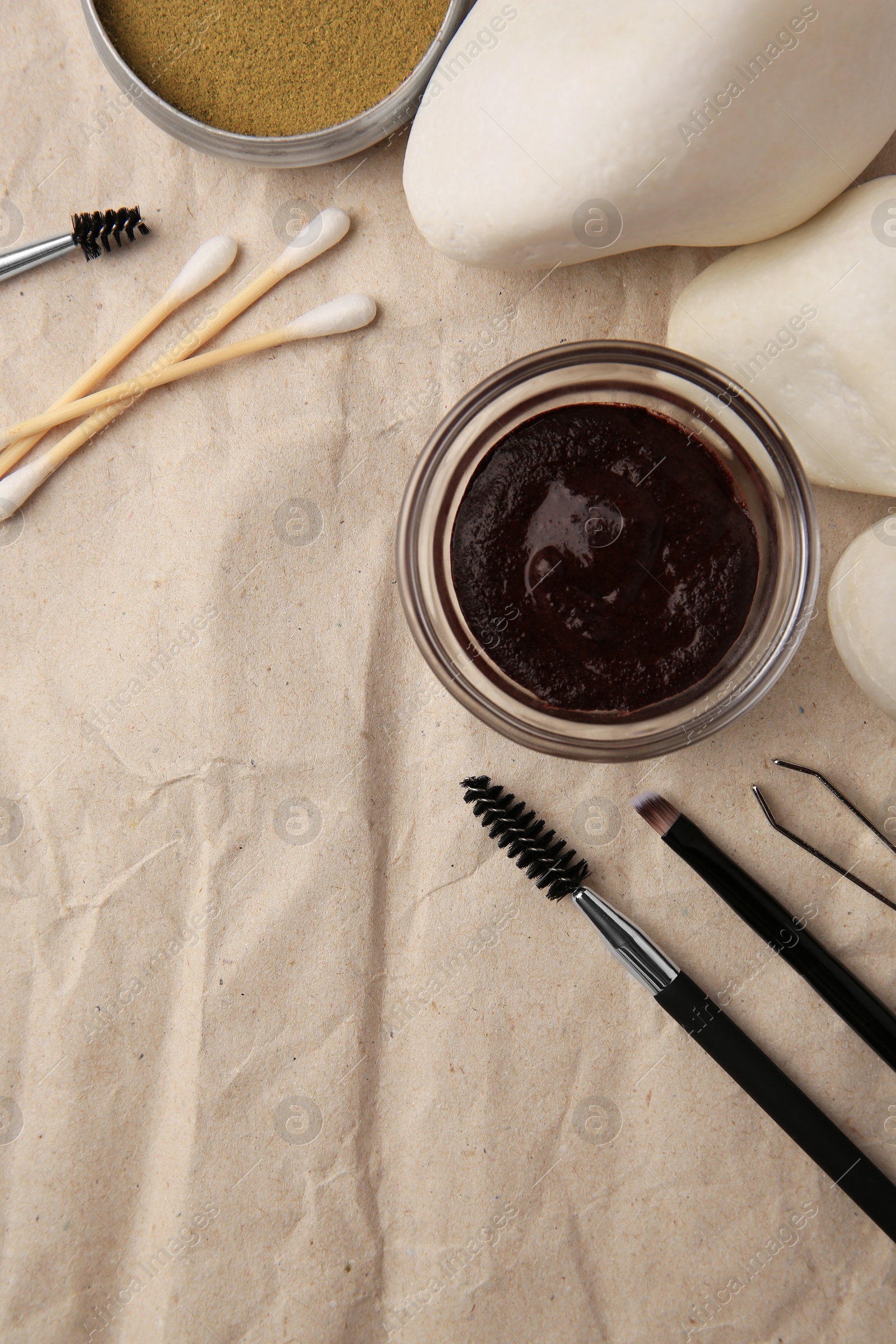 Photo of Flat lay composition with eyebrow henna and tools on crumpled paper. Space for text