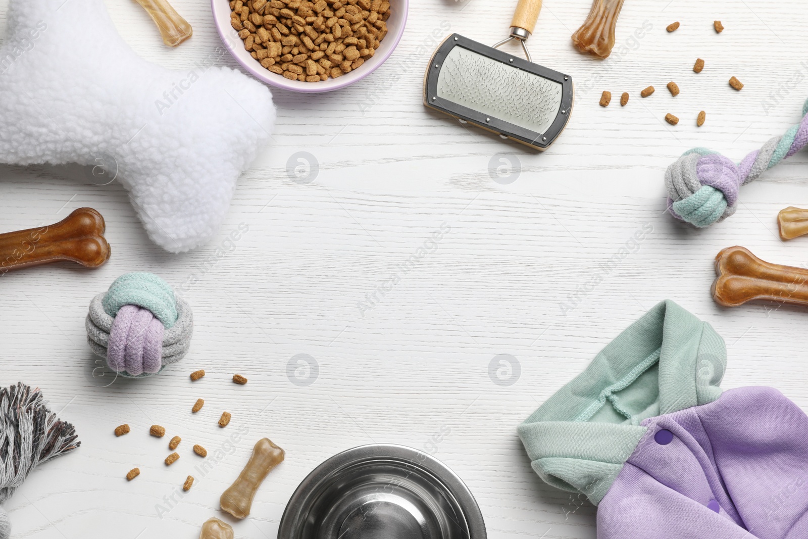 Photo of Flat lay composition with dog clothes, food and accessories on white wooden table. Space for text