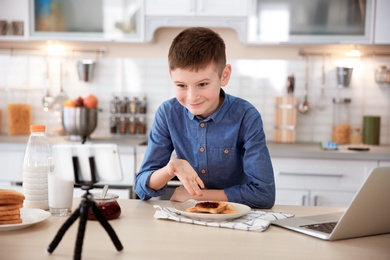 Photo of Cute little blogger with food recording video on kitchen
