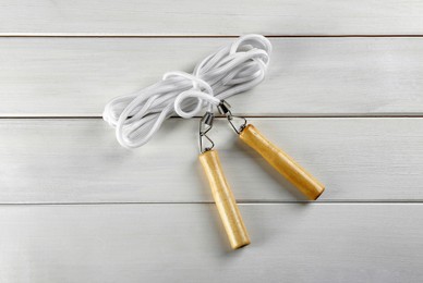 Photo of Skipping rope on white wooden table, top view. Sports equipment