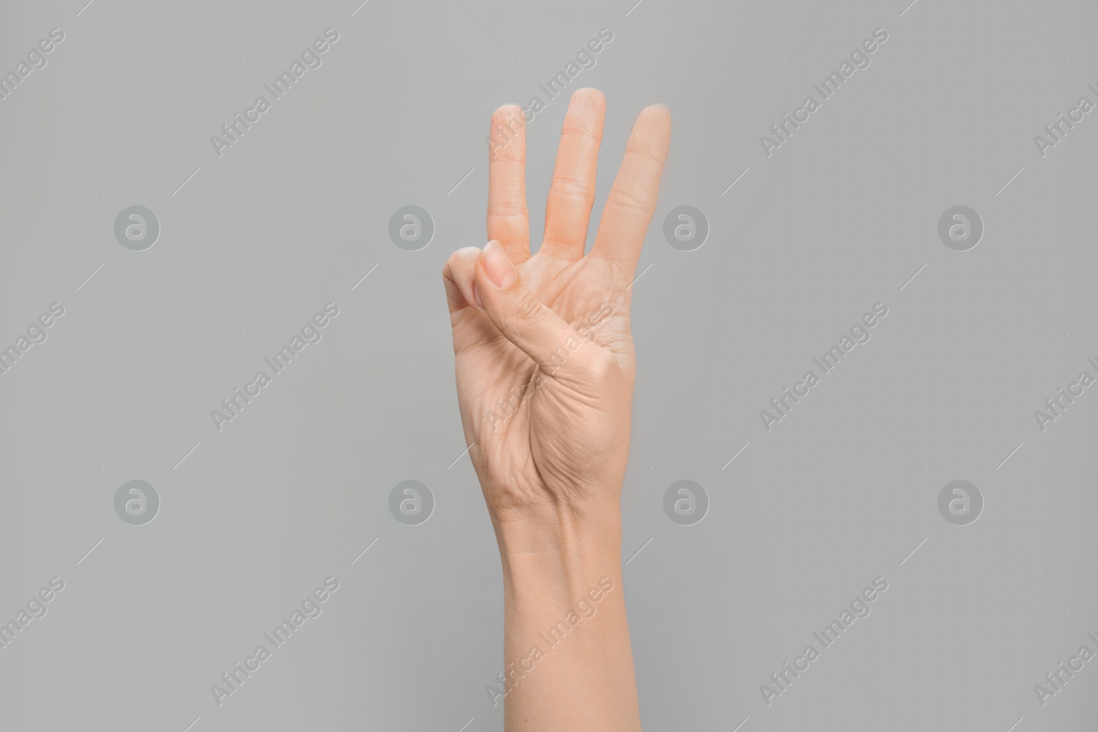 Photo of Woman showing W letter on grey background, closeup. Sign language