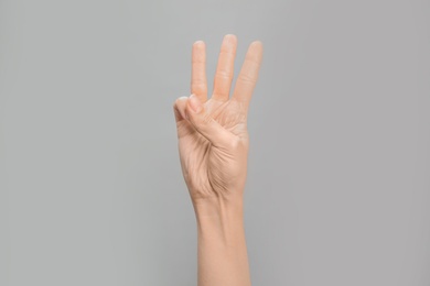 Photo of Woman showing W letter on grey background, closeup. Sign language