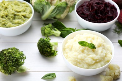 Photo of Bowls with different tasty puree and ingredients on white wooden table