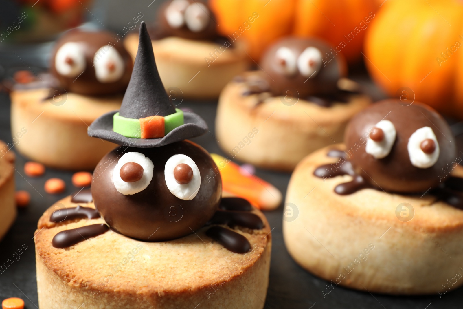 Photo of Delicious biscuits with chocolate spiders on slate plate, closeup. Halloween celebration