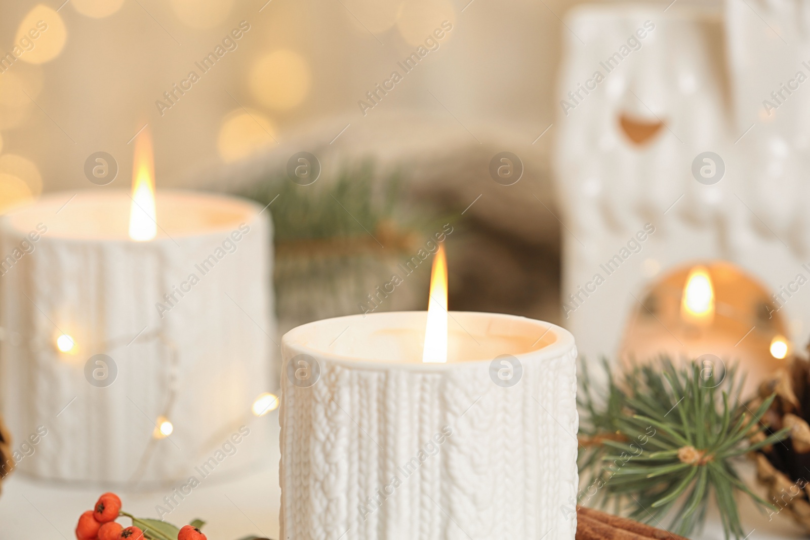 Photo of Holders with burning candles and decoration against blurred Christmas lights, closeup