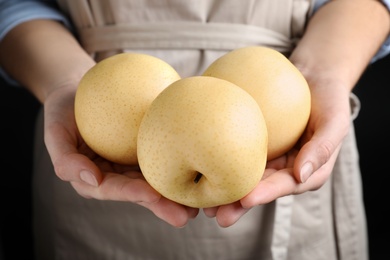 Photo of Woman holding ripe apple pears on black background, closeup