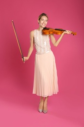 Photo of Beautiful woman with violin on pink background