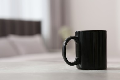 Black ceramic mug on table indoors. Mockup for design