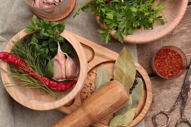 Photo of Mortar with pestle and different ingredients on wooden table, flat lay
