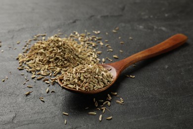 Spoon with fennel seeds on gray table, closeup