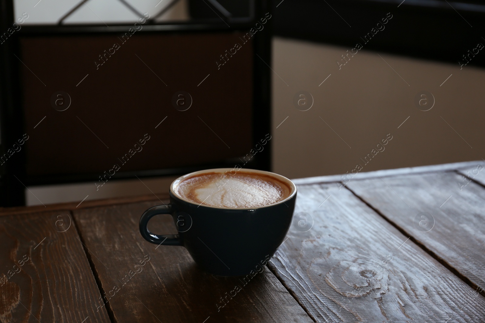 Photo of Cup of aromatic coffee on wooden table in cafe