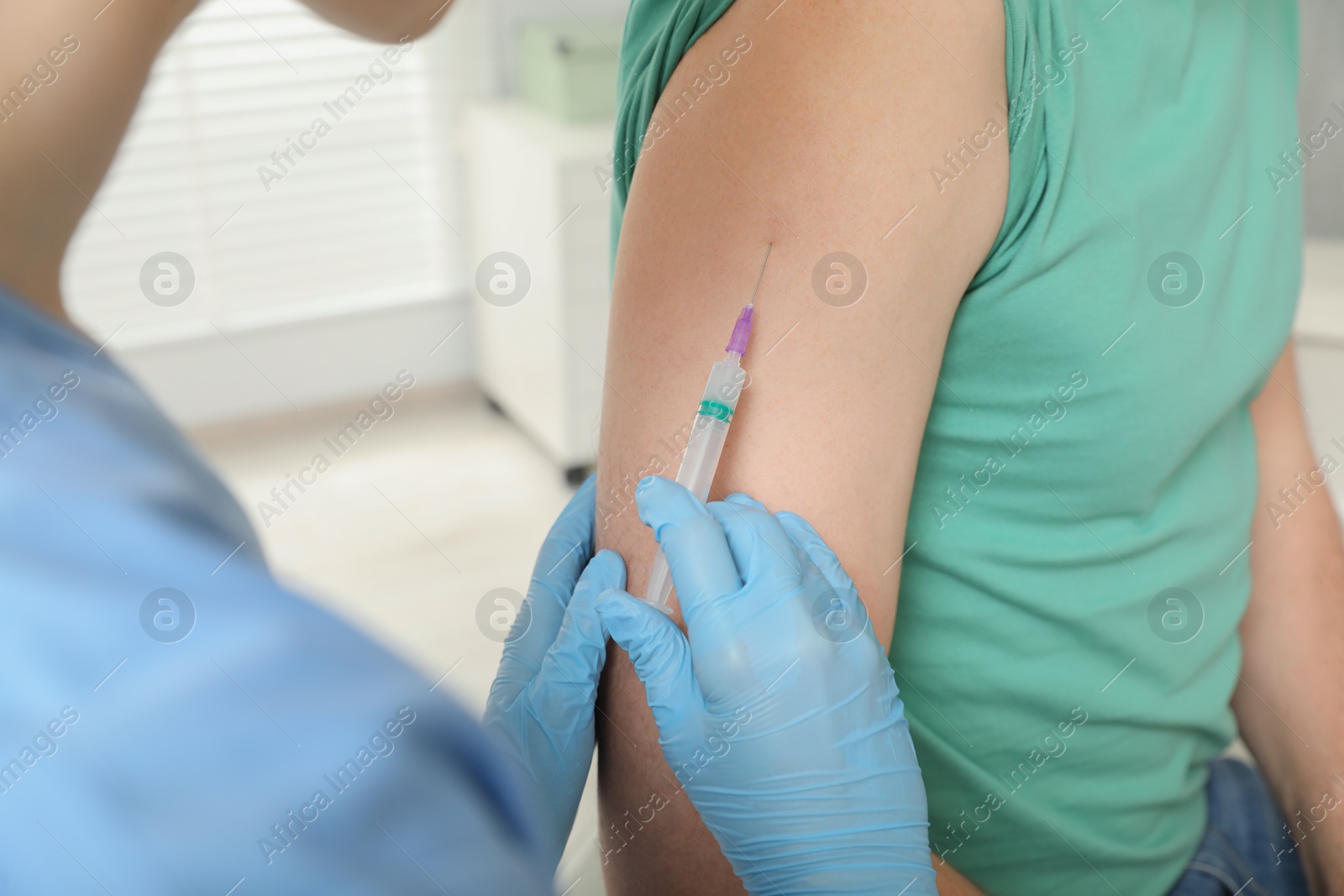 Photo of Doctor giving hepatitis vaccine to patient in clinic, closeup