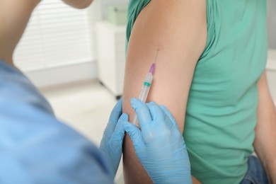 Photo of Doctor giving hepatitis vaccine to patient in clinic, closeup