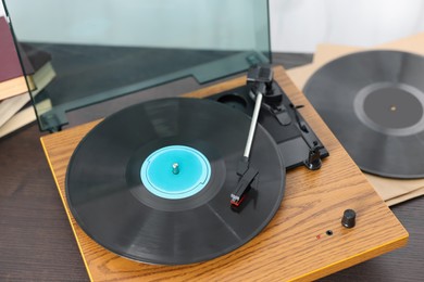 Photo of Retro turntable with vinyl record on wooden table