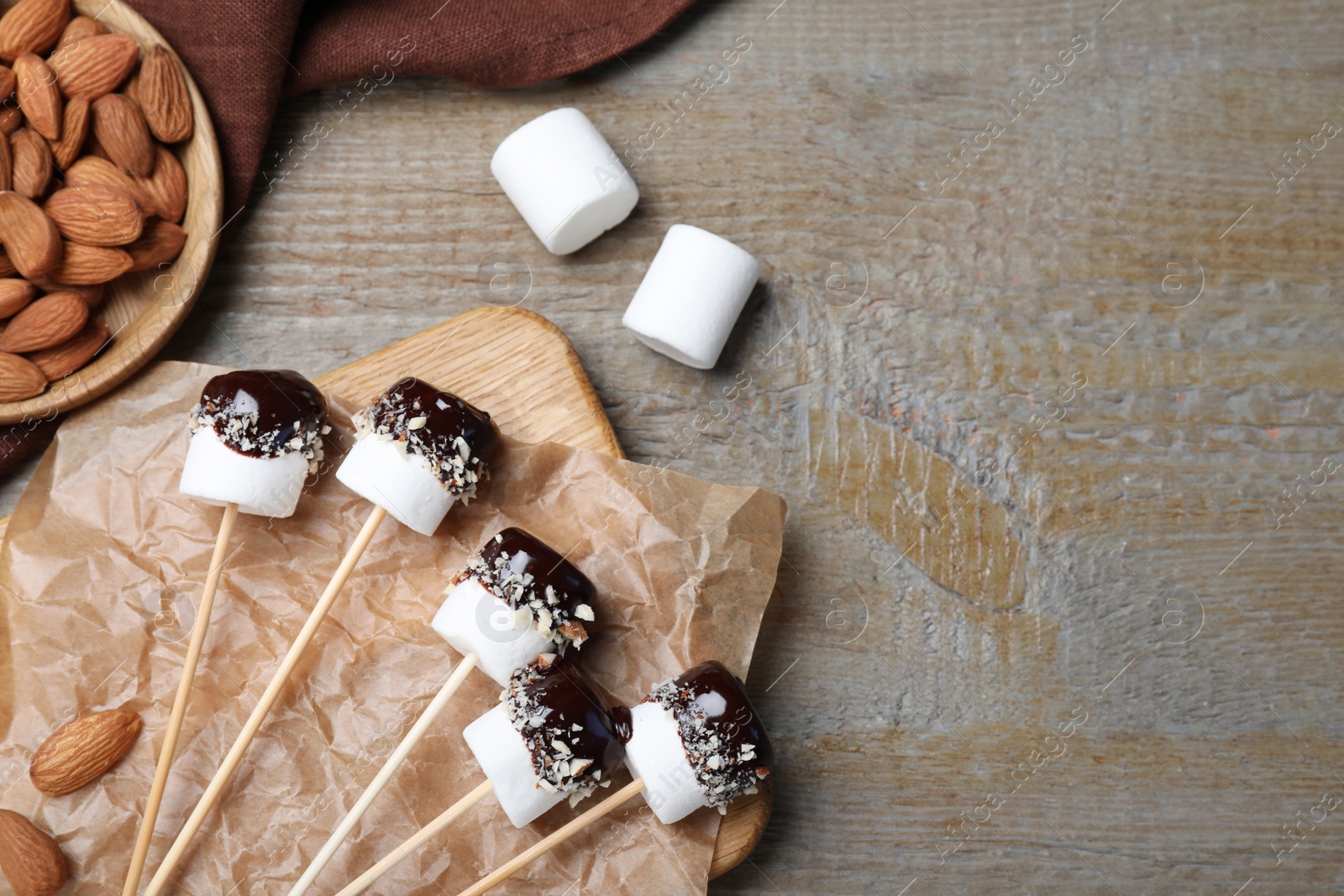 Photo of Delicious marshmallows covered with chocolate on wooden table, flat lay. Space for text