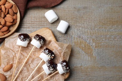 Delicious marshmallows covered with chocolate on wooden table, flat lay. Space for text