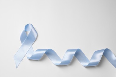 Photo of International Psoriasis Day. Light blue ribbon as symbol of support on white background, top view