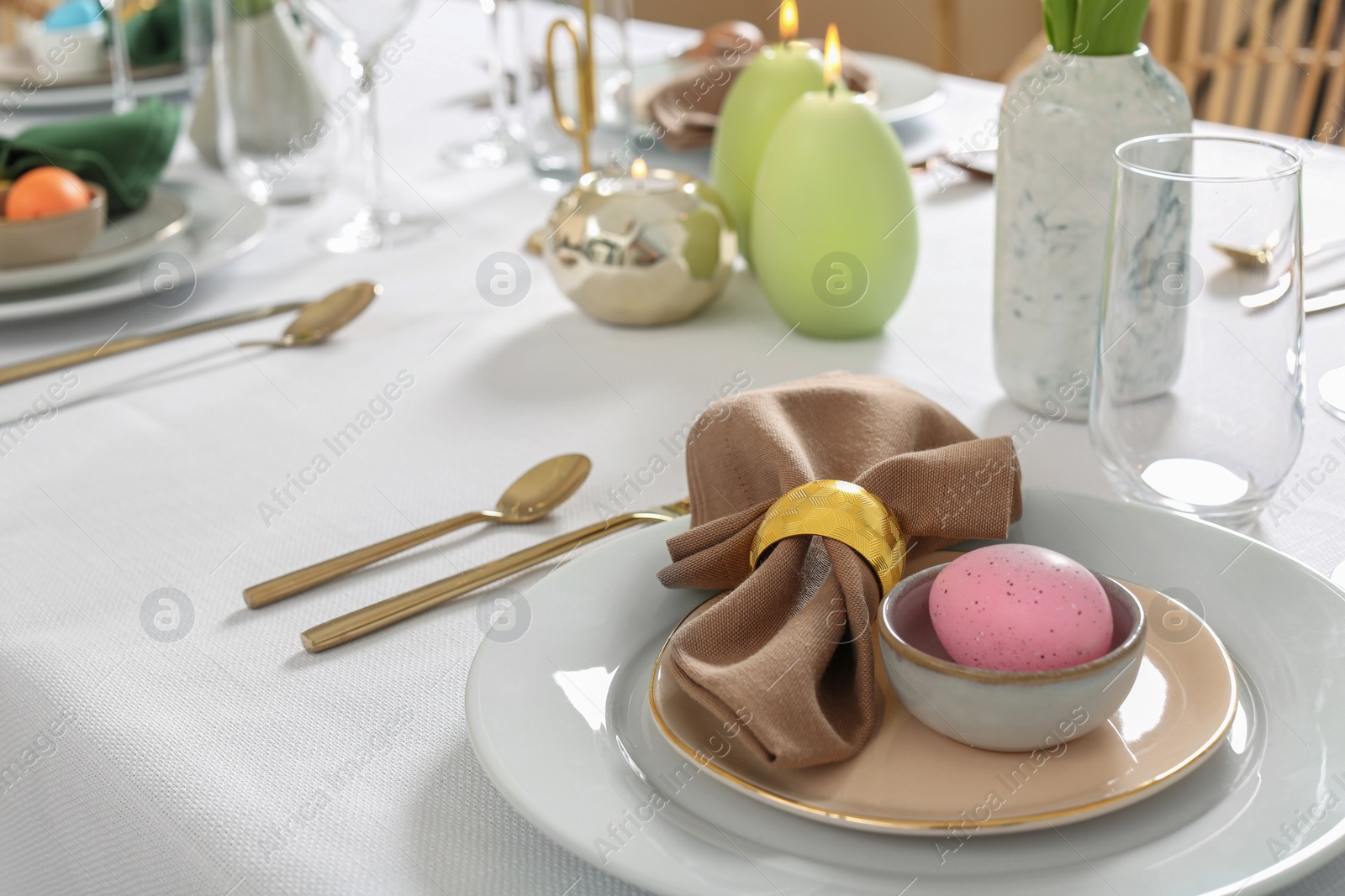 Photo of Festive Easter table setting with painted eggs and burning candles