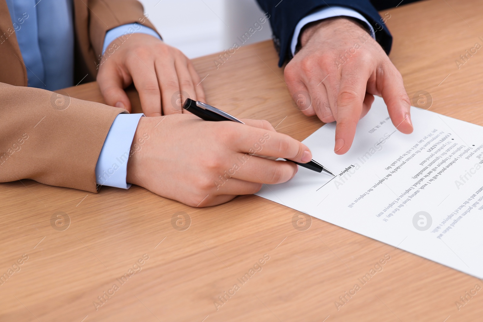 Photo of Businesspeople signing contract at wooden table, closeup of hands