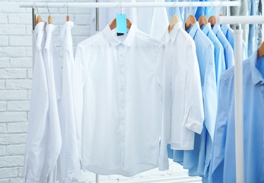 Photo of Rack with clean clothes on hangers after dry-cleaning indoors