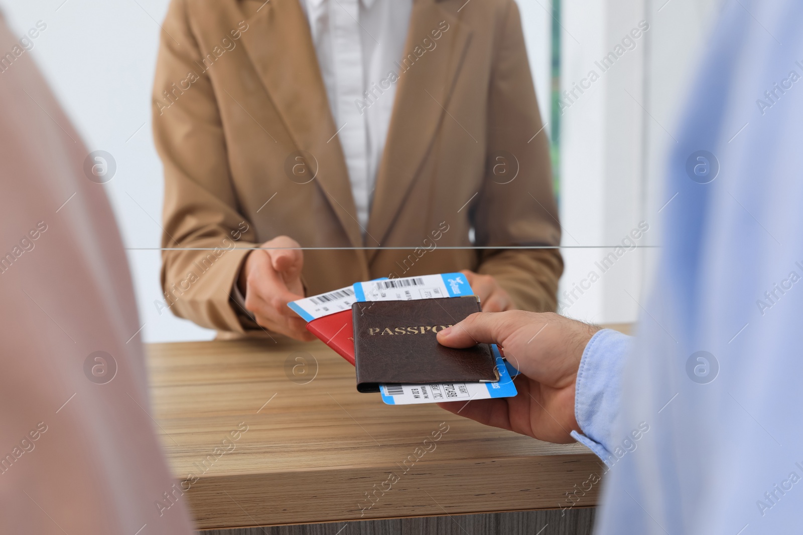 Photo of Man giving passports with tickets to agent at check-in desk in airport, closeup
