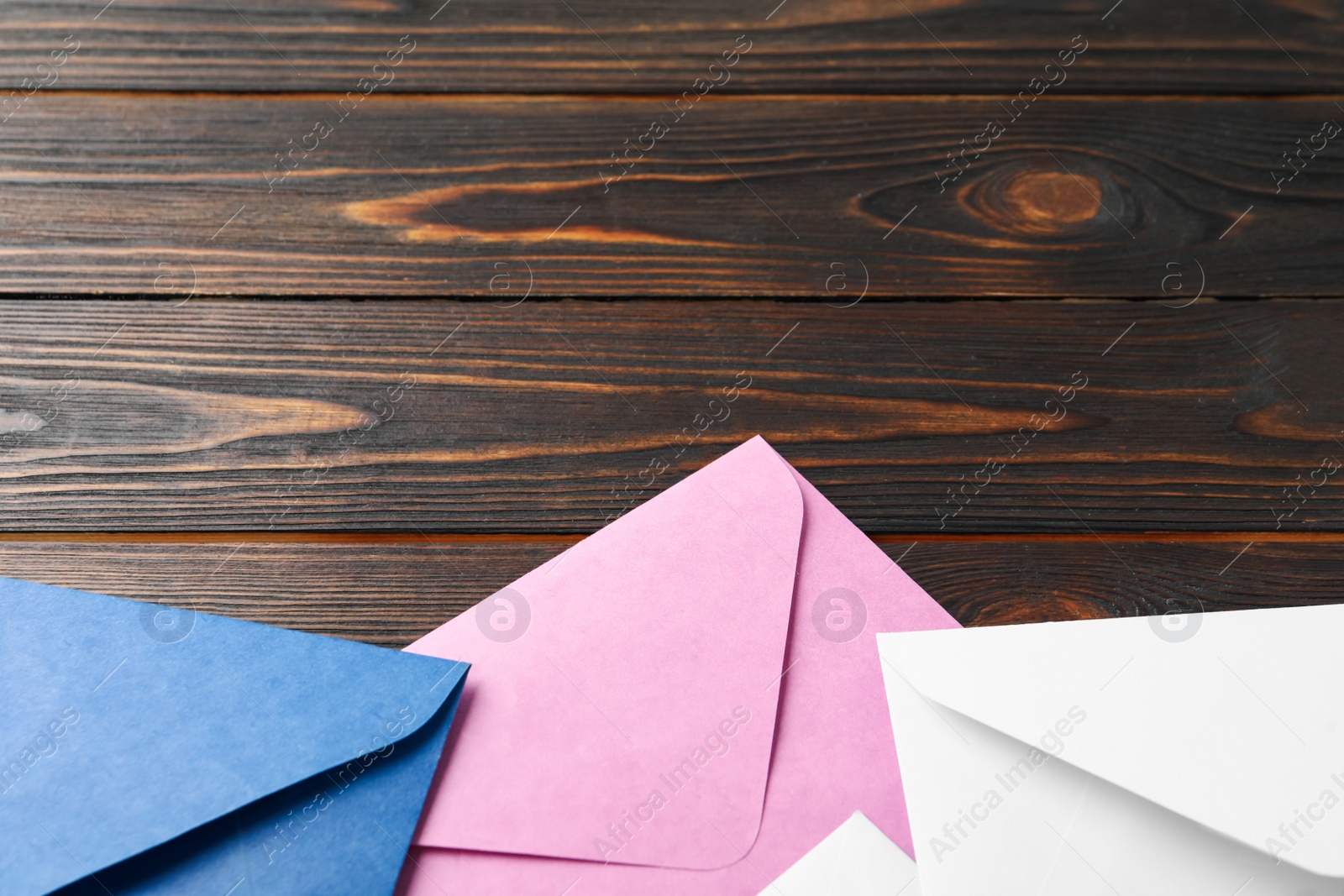 Photo of Colorful paper envelopes on wooden background, closeup. Space for text